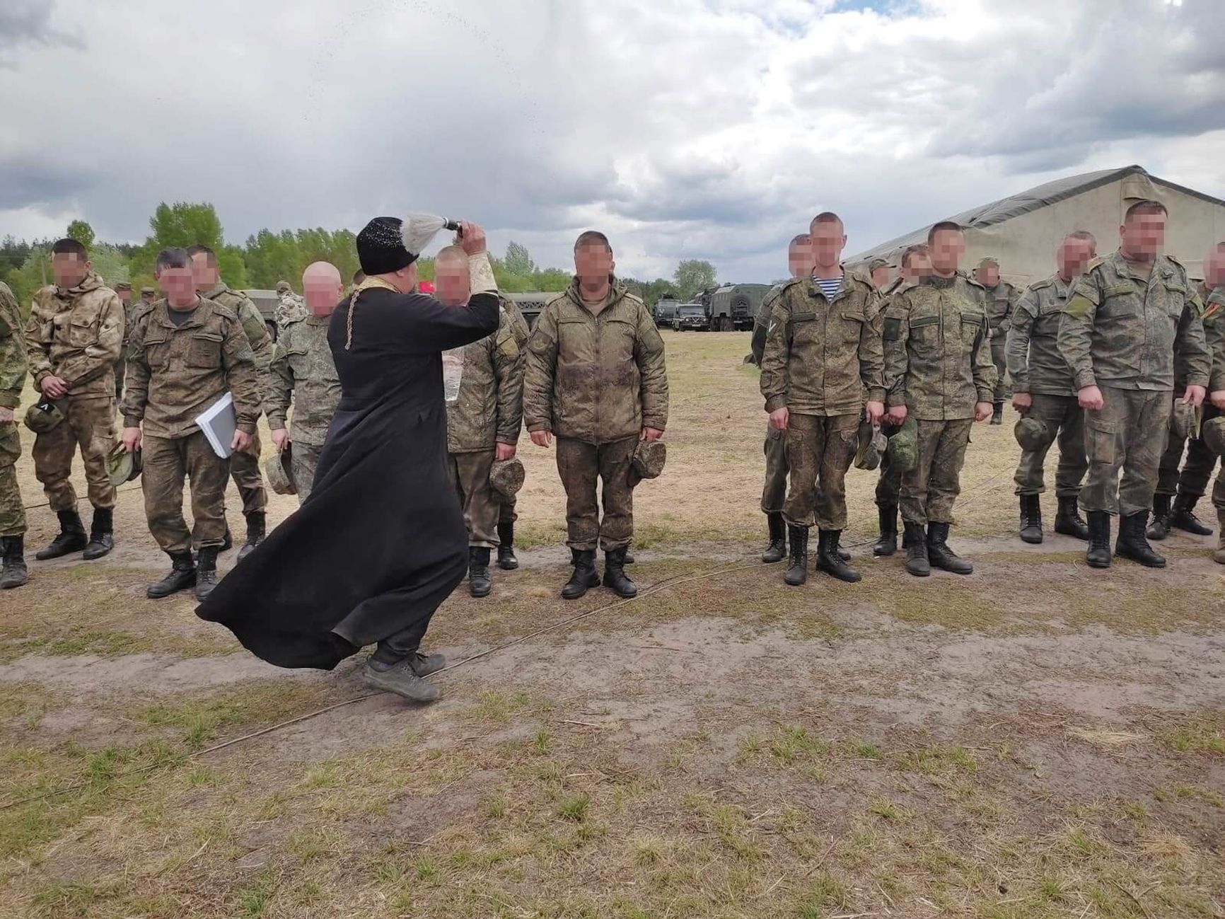 A priest administers communion to the “SMO” fighters