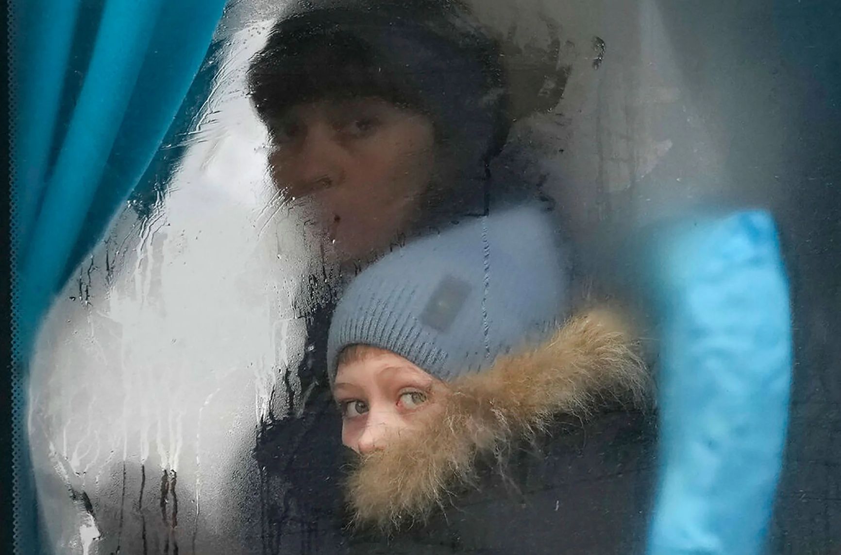 Женщина и ребенок выглядывают из окна автобуса на выезде из Северодонецка, Луганская область, Украина, 24 февраля