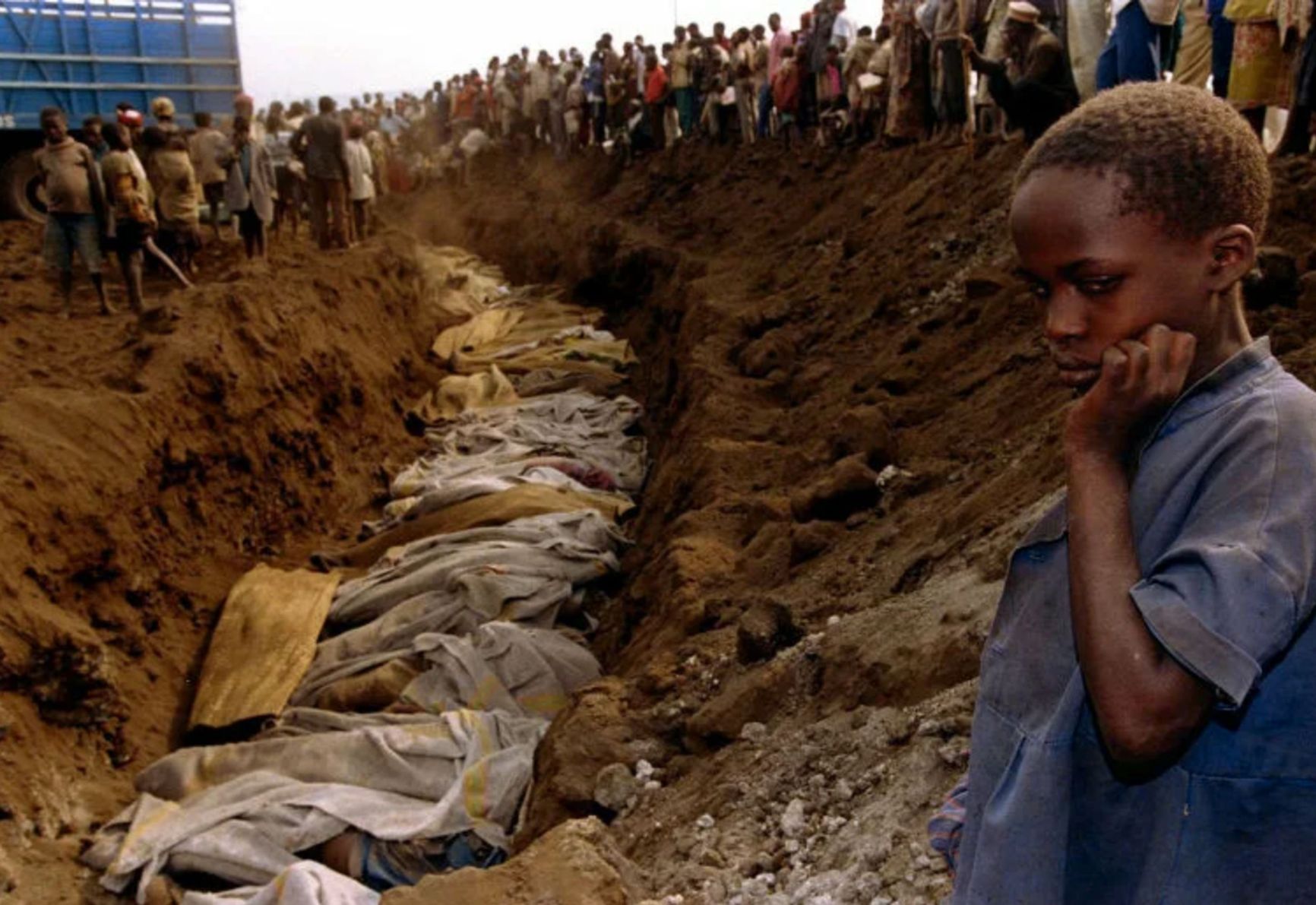 A Tutsi boy in front of a mass grave where all his relatives are buried