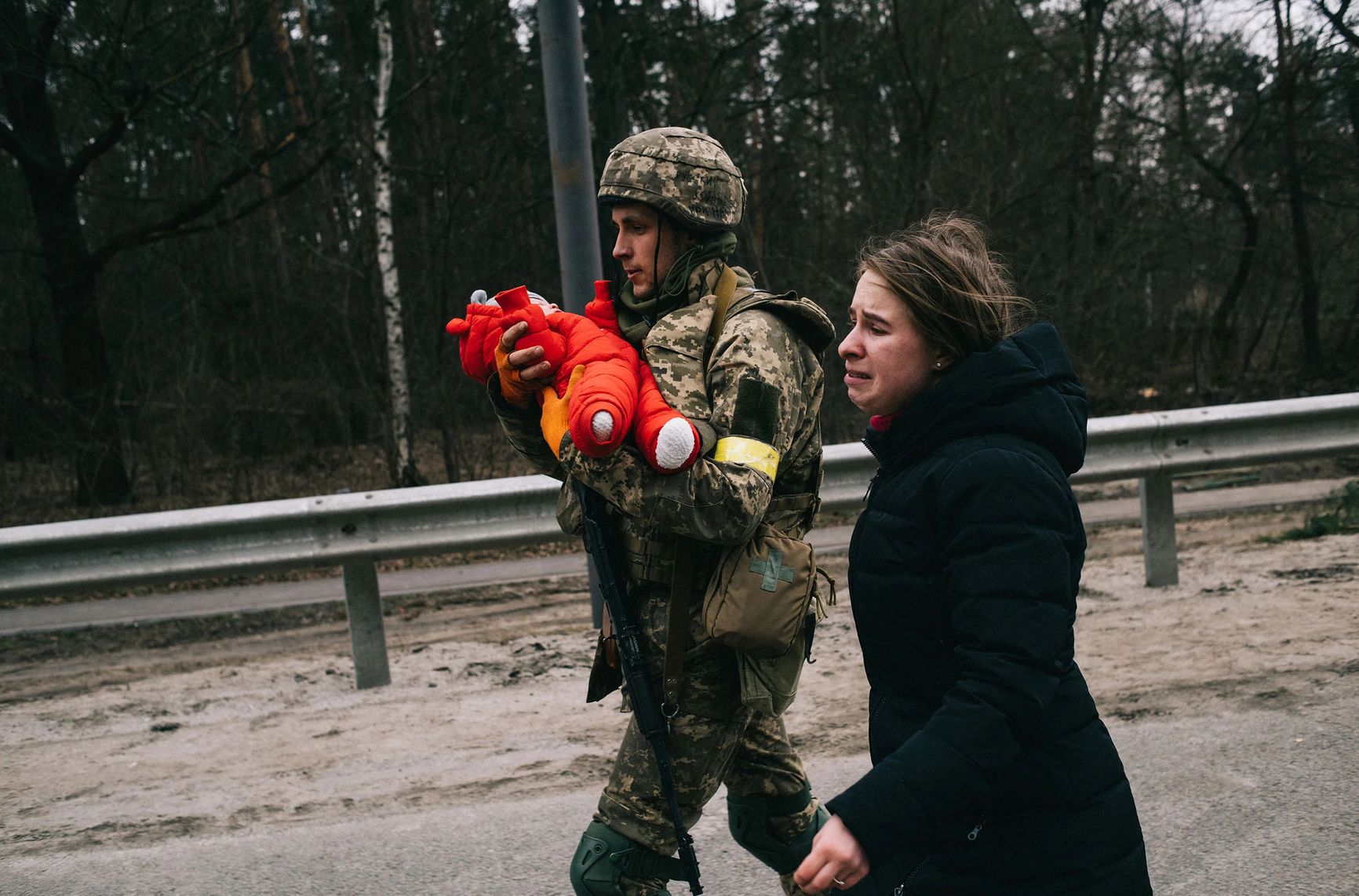 Украинский солдат помогает Юлии Павлюк и ее дочери Эмме эвакуироваться из Ирпеня, который российские войска стремились захватить во время попытки окружить столицу 5 марта