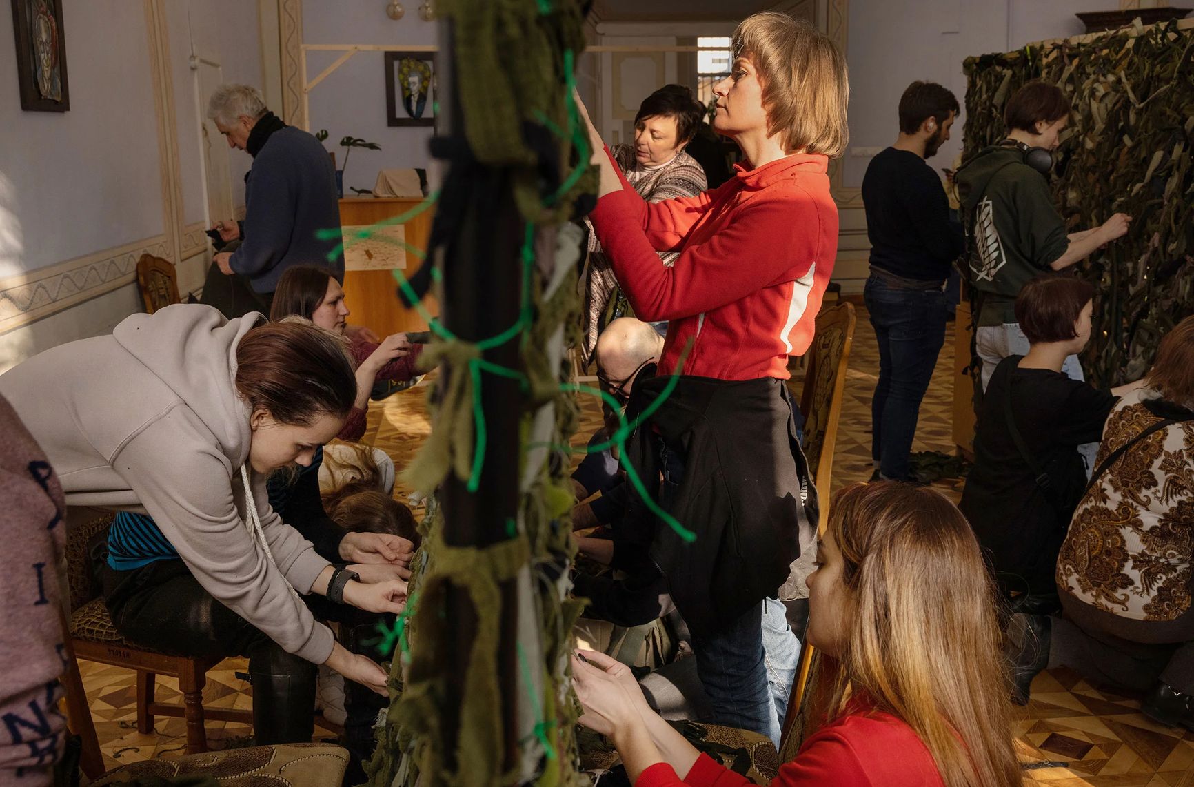 Добровольцы в библиотеке в центре Львова, Украина, плетут камуфляжные сети для отправки солдатам на передовую, 7 марта