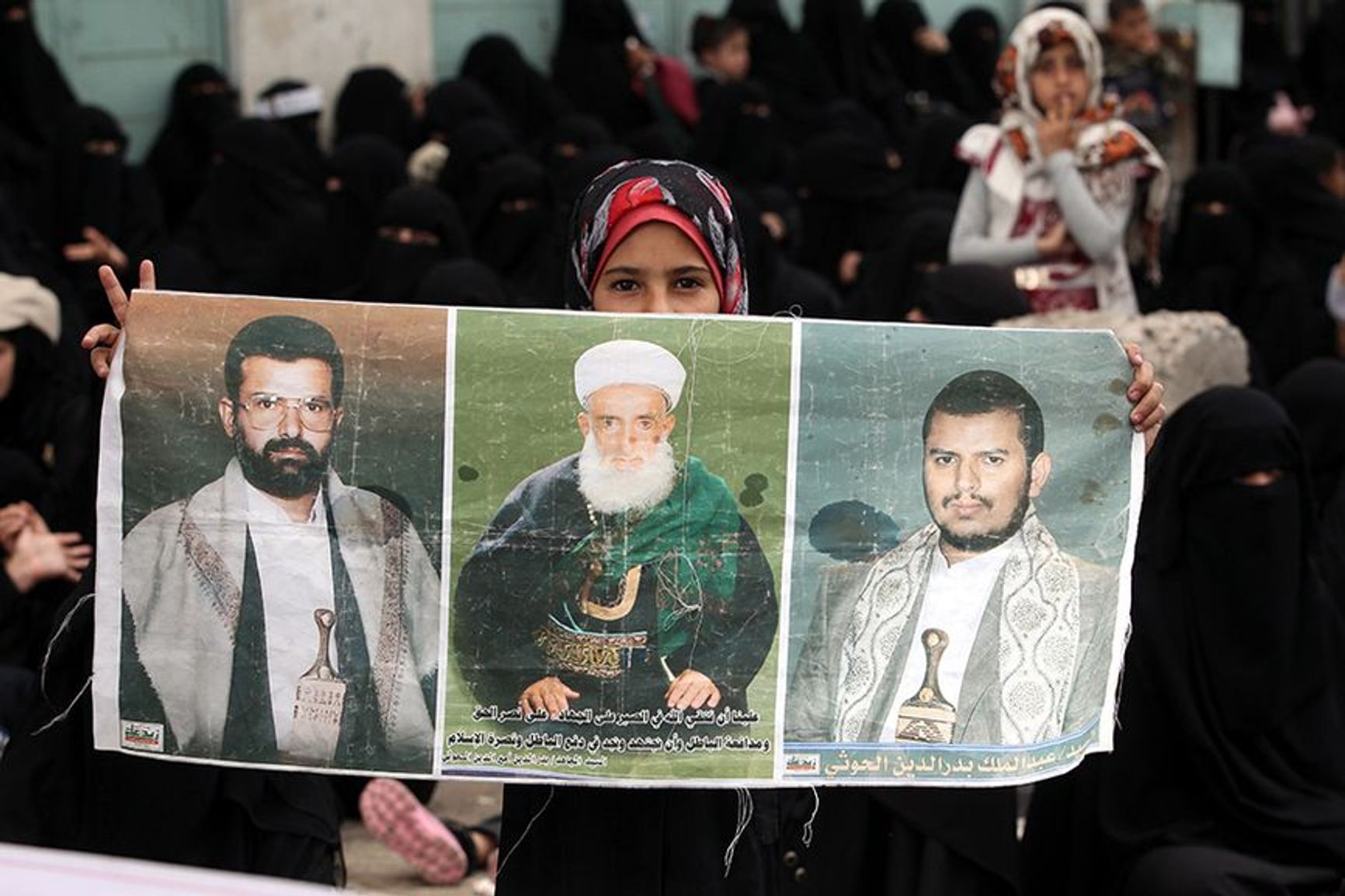 The poster shows Hussein al-Houthi (left), Abdul-Malik al-Houthi (right) and their father Badreddin al-Houthi (center)