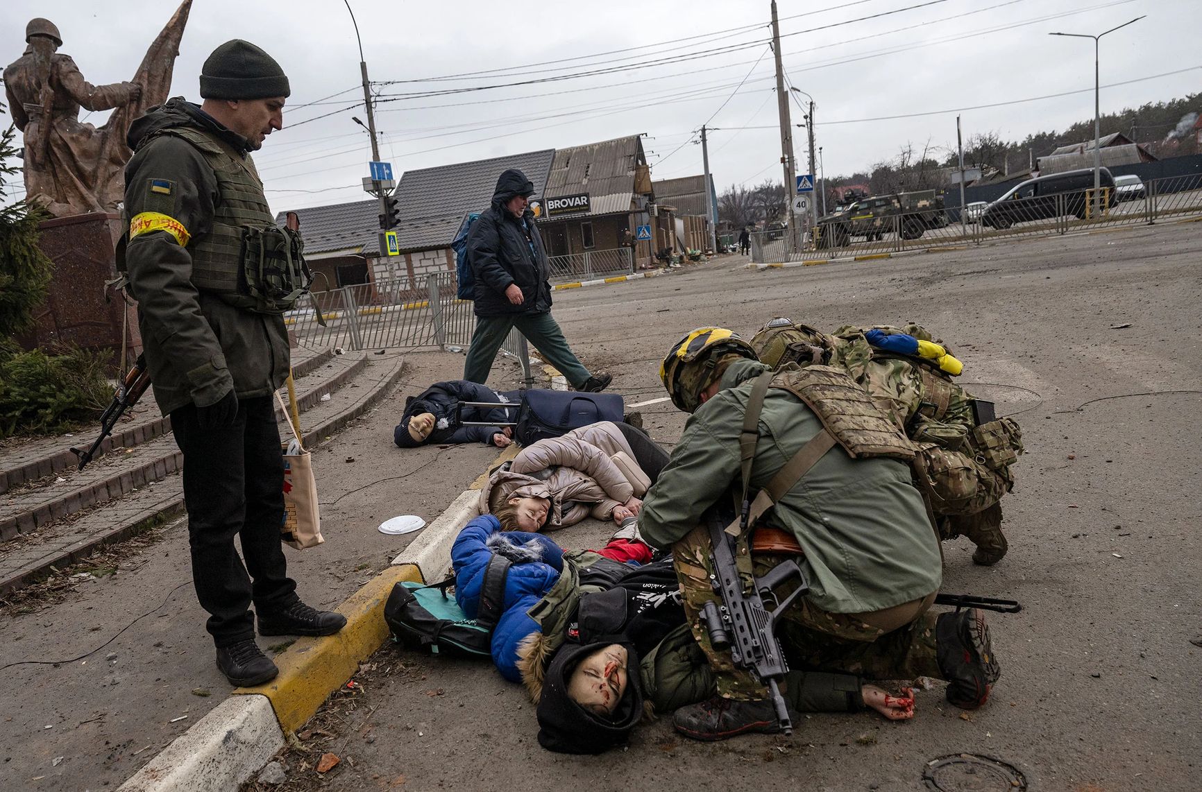 Украинские солдаты осматривают тела погибших мирных жителей, в том числе Татьяны Перебийнис и двух ее детей, которые были смертельно ранены российским минометным снарядом во время эвакуации из Ирпеня, Украина, 6 марта. Также погиб доброволец, помогавший семье