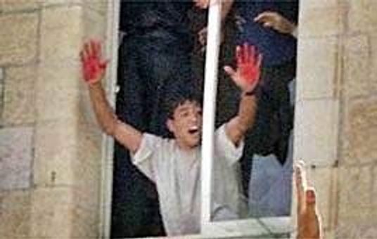 Aziz Salha, one of the lynchers, waving his blood-stained hands from the police station window